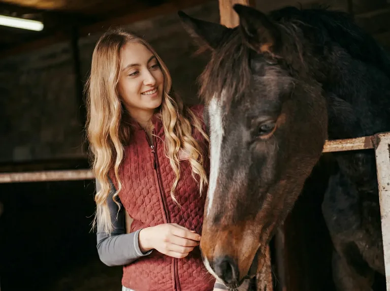 Woman petting a horse's head.